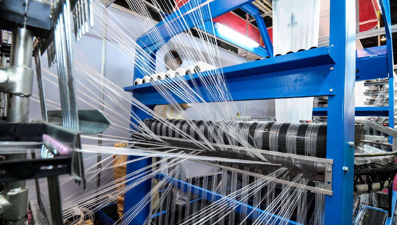 Precision threads running through a blue textile weaving machine